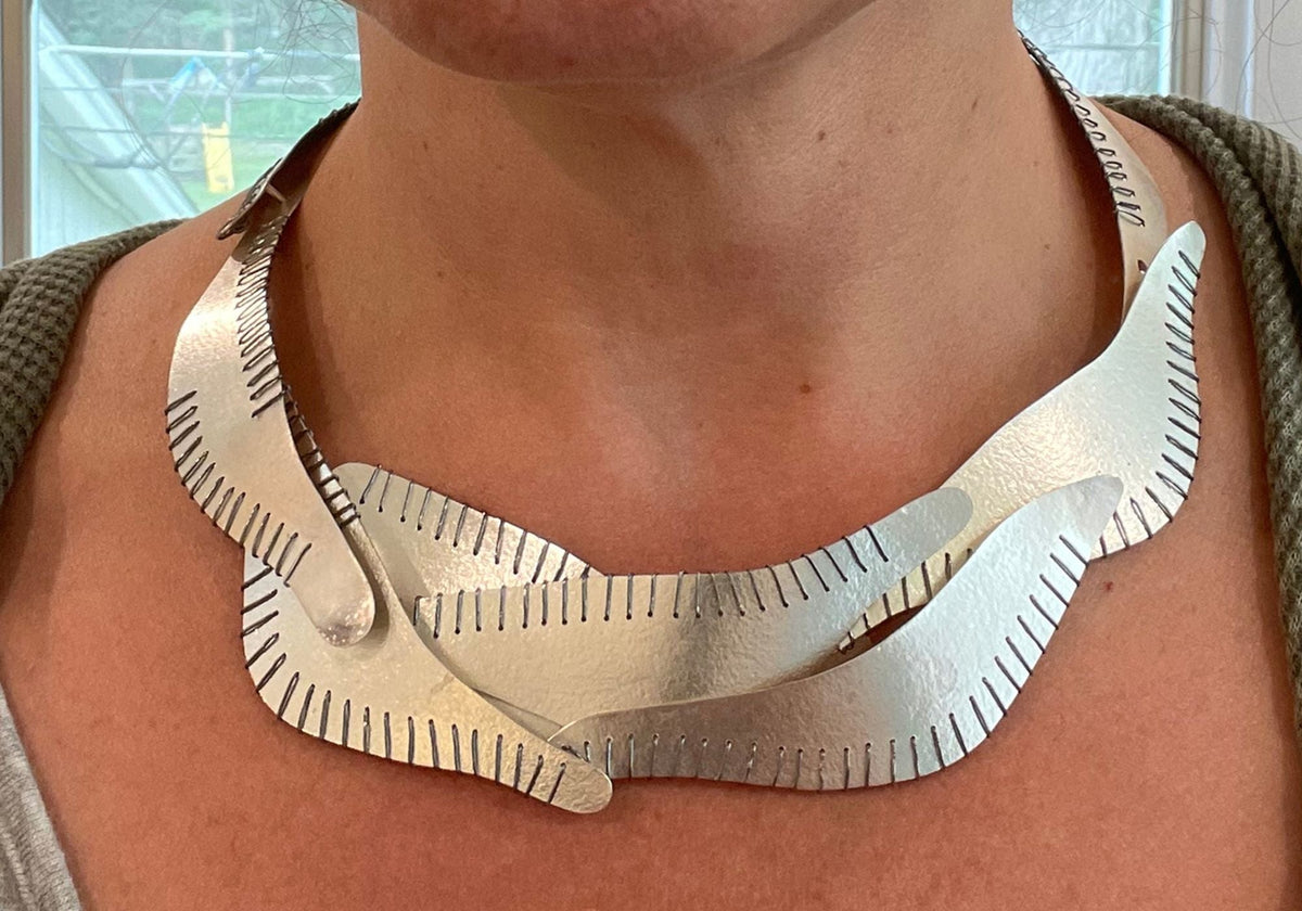 Suzanne Schwartz Holiday Elegance — dramatic wide handmade Argentium silver stitched bib collar necklace, worn close-up