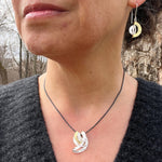 Model wearing silver and gold earrings and necklace.