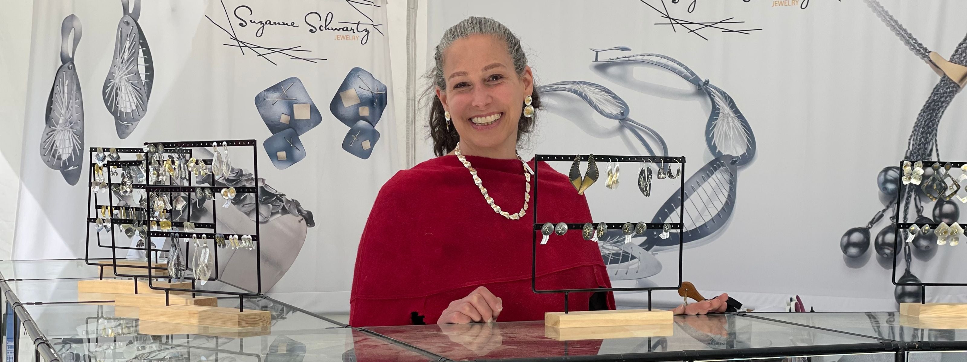 Suzanne Schwartz at craft show booth with handmade jewelry display — Galleries and Stores
